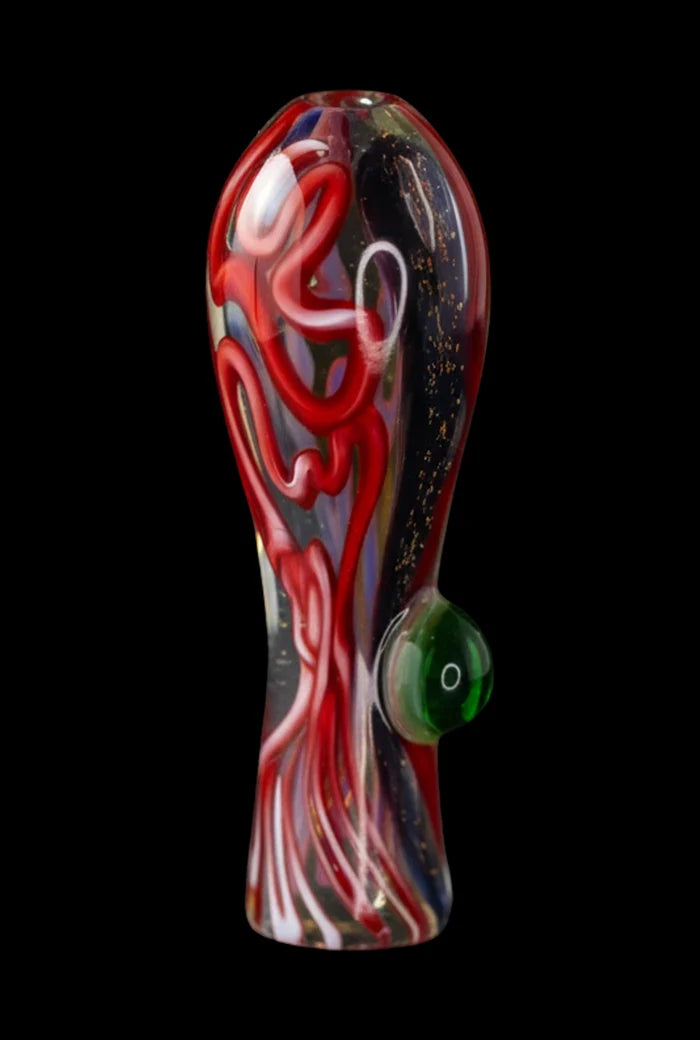 Close-up front view of the Brain Fold Chillum Pipe showing a glossy red swirl pattern and a green side bubble against a black background.