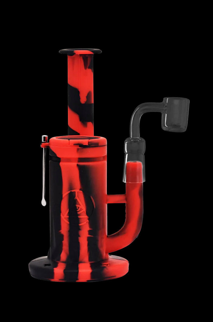 Red and black silicone dab rig with a quartz banger and dab tool against a black background.