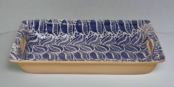 Rectangular ceramic baking dish with blue leaf pattern on a wooden surface